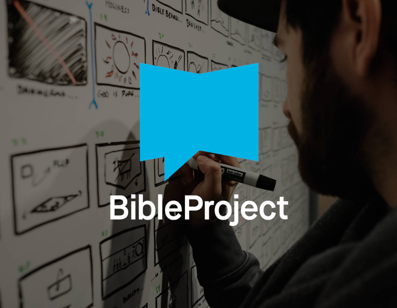 Mann im Hintergrund zeichnet im Stift auf einer Tafel. Im Vordergrund das Logo von BibleProject